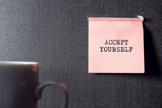 Blur coffee cup on gray rough textured wallpaper with copy space , pink note with text ACCEPT YOURSELF , concept of self acceptance , ability to embrace all facets of oneself , positive or negative