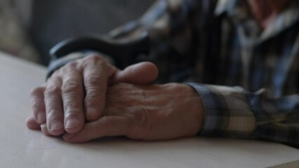 close-up of the old man's hand on the table, selective focus. pensioner thinks with folded arms, elderly lonely people, real people are inside