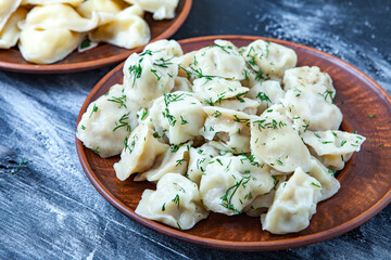 Traditional russian pelmeni or ravioli, dumplings with meat on wood black background. Russian food and russian kitchen concept.