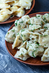Traditional russian pelmeni or ravioli, dumplings with meat on wood black background. Russian food and russian kitchen concept.