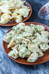Traditional russian pelmeni or ravioli, dumplings with meat on wood black background. Russian food and russian kitchen concept.