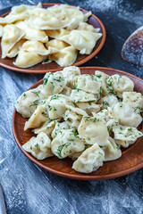 Traditional russian pelmeni or ravioli, dumplings with meat on wood black background. Russian food and russian kitchen concept.