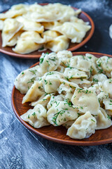 Traditional russian pelmeni or ravioli, dumplings with meat on wood black background. Russian food and russian kitchen concept.