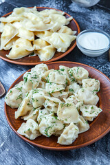 Traditional russian pelmeni or ravioli, dumplings with meat on wood black background. Russian food and russian kitchen concept.