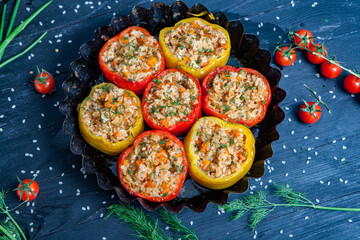 Stuffed pepper. Stewed pepper
 with rice and minced meat. Baked peppers in a cast iron pan on a black background. Healthy Romanian food.
