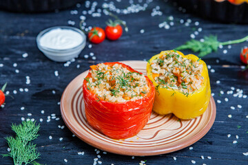 Stuffed pepper. Stewed pepper
 with rice and minced meat. Baked peppers in a cast iron pan on a black background. Healthy Romanian food.
