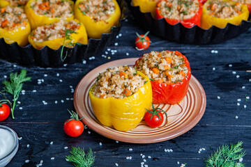 Stuffed pepper. Stewed pepper
 with rice and minced meat. Baked peppers in a cast iron pan on a black background. Healthy Romanian food.
