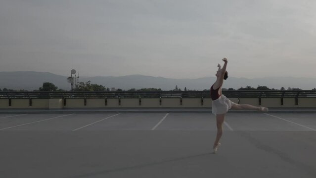 Side chase of a ballet dancer on a parkade roof