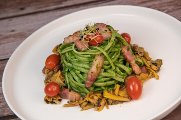 Recipe for spaghetti with spinach cream and smoked bacon, tomatoes and chanterelle mushrooms. High quality photo