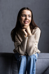 Happy young pretty hispanic woman looking at camera sitting on sofa at cozy home.