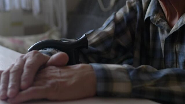 close-up pensioner with a walking stick sits at an empty table.selective focus.old man's hands on the table.old age and need.theme elderly lonely people