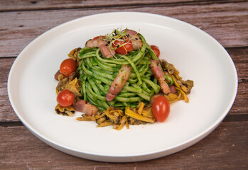 Recipe for spaghetti with spinach cream and smoked bacon, tomatoes and chanterelle mushrooms. High quality photo