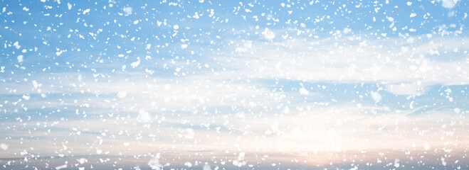 Snow falling over blue sky background