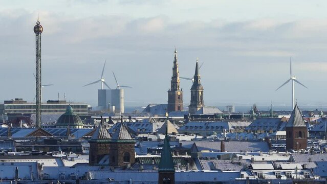 Copenhagen, Denmark Snow covers the rooftops of the city skyline, church spires, and wind turbines. 
