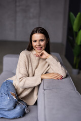 Happy young woman lying on couch and relaxing at home