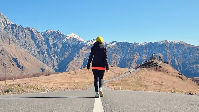 Tourist walk go towards Gergeti trinity church in Georgia. Famous Gergeti Trinity Tsminda Sameba Church . Beautiful Georgian Landscape In fall, autumn Early Winter