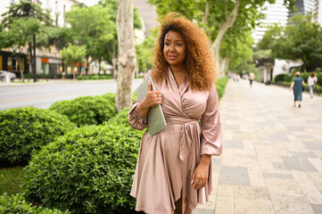 Attractive happy stylish plus size African American woman student freelancer afro hair with laptop...
