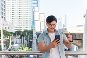 Asian man with glasses using smartphone in the city.