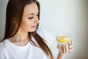 Beautiful youthful lady refreshing herself with lemon water