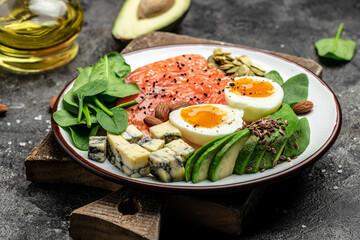Keto diet food, salmon, avocado, cheese, egg, spinach and nuts. Ketogenic low carbs diet concept. Ingredients for healthy foods. Long banner format. top view
