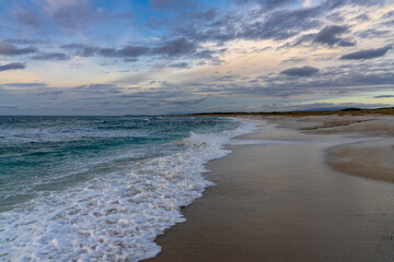 empty white sand beach and sand dunes at sunset with turquoise water in Sardinia