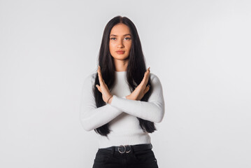 Portrait of brunette young woman hold hands crossed angry mood, standing over white studio...