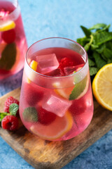 Raspberry lemonade drink in glass on blue background