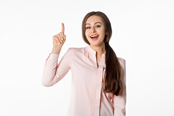 Enthusiastic girl points finger up, shows logo banner, product advertisement. Smiling young woman standing against white studio background