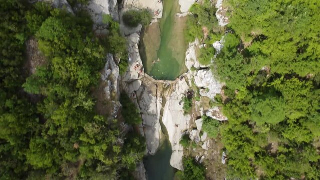 Dammed river flowing from the mountain. People swimming in man made pond. Bird eye view.