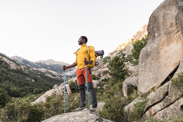 Young strong African American traveler on top of mountain, observe his great achievement for...
