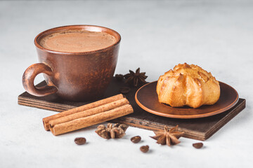 Hot chocolate drink in a cup and sweet bakery eclair dessert, cinnamon stick and star anise on...
