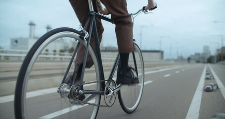 Side shot of young man ride bike on way to work in urban industrial area of city. Fast and confident cyclist ride commuter bicycle to school. Commuting as new way to travel and move around - Powered by Adobe