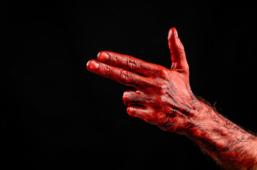 Bloody male hand gesturing shows a gun against black background.