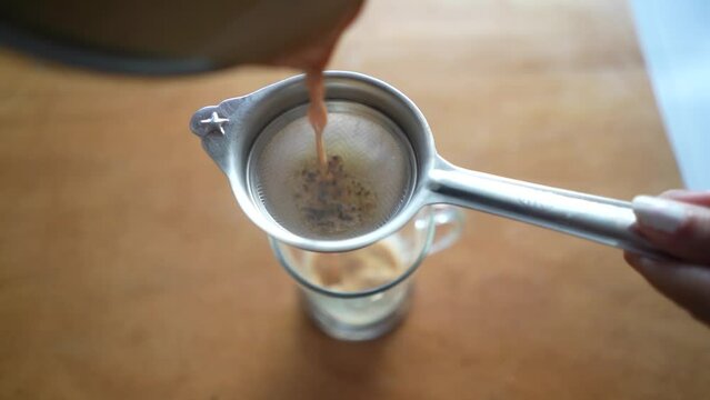 Pouring tea chai in a CUP on wooden table
