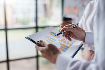 Businesspeople at a meeting pointing at graphs to calculate, plan, analyze, create graphs and charts to show business growth to plan new business expansion in the future.