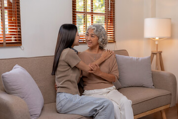 Obraz premium Beautiful Asian woman is taking care of her mother at home in the living room, sitting and resting, having a happy and warm conversation as a mother and daughter.