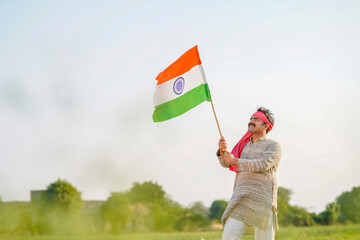 Indian farmer holding indian flag at agriculture field.