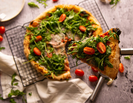 Flat Lay Photography, Pizza With Arugula And Tomatoes On Laid On A Tray With One Of The Pieces Cut Out