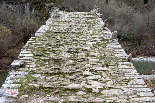Greece Epirus. Plakida or Kalogeriko ancient stone bridge over river, above dry nature background.