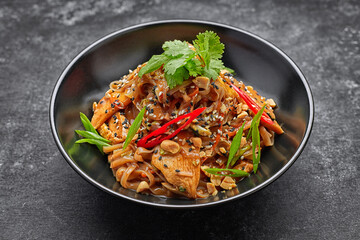 Noodles with chicken and vegetables, on a black plate