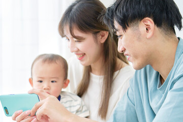 家で赤ちゃんとスマホを見る両親