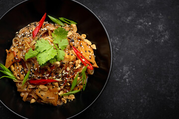 Noodles with chicken and vegetables, on a black plate
