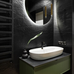 Oval white washbasin in modern black bathroom