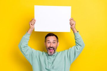 Photo of excited overjoyed mature age man wear khaki sweatshirt hold paper banner empty space...