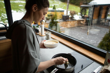 a young woman prepares delicious pancakes in the kitchen