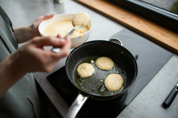 a young woman prepares delicious pancakes in the kitchen