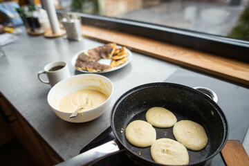a young woman prepares delicious pancakes in the kitchen