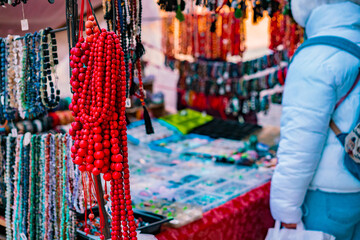 Fototapeta na wymiar A lot of various colourful beads in different colours are selling on the outdoor. Traditional handmade Jewellery. Red. City. Market. Trade. Trading. Necklaces. Street