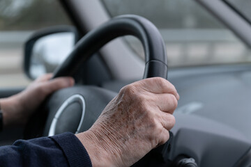 Une personne agée qui conduit une voirure les mains sur le volant