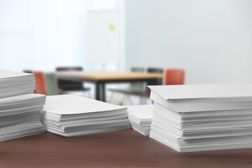 Stacked sheets of paper on wooden table in office, space for text